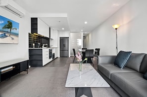 Een moderne woonkamer met een bank, een salontafel en een eethoek met stoelen.