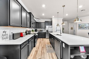 A modern kitchen with dark cabinets, a white countertop, and stainless steel appliances. - New Listing! Classic Mickey! Theater! Resort 7 mi 2 Disney! 2166 (Davenport)