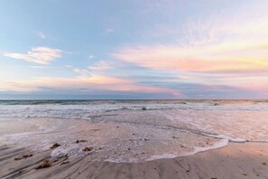 A beach with waves, a clear sky, and a sunset. - Paradise Spaces Resort (St. Augustine)