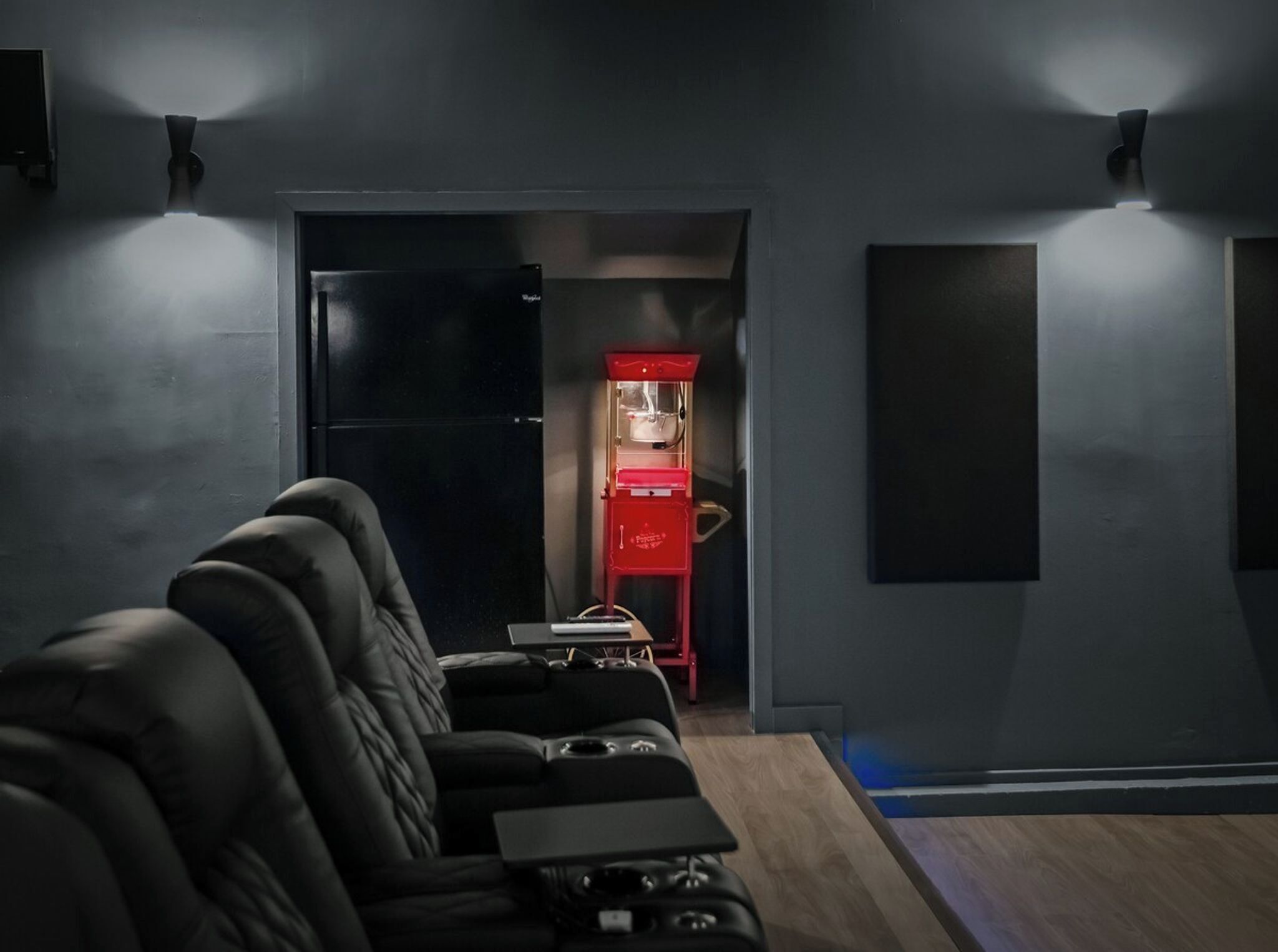 Une pièce moderne avec un canapé en cuir noir, un distributeur automatique rouge et un réfrigérateur noir.