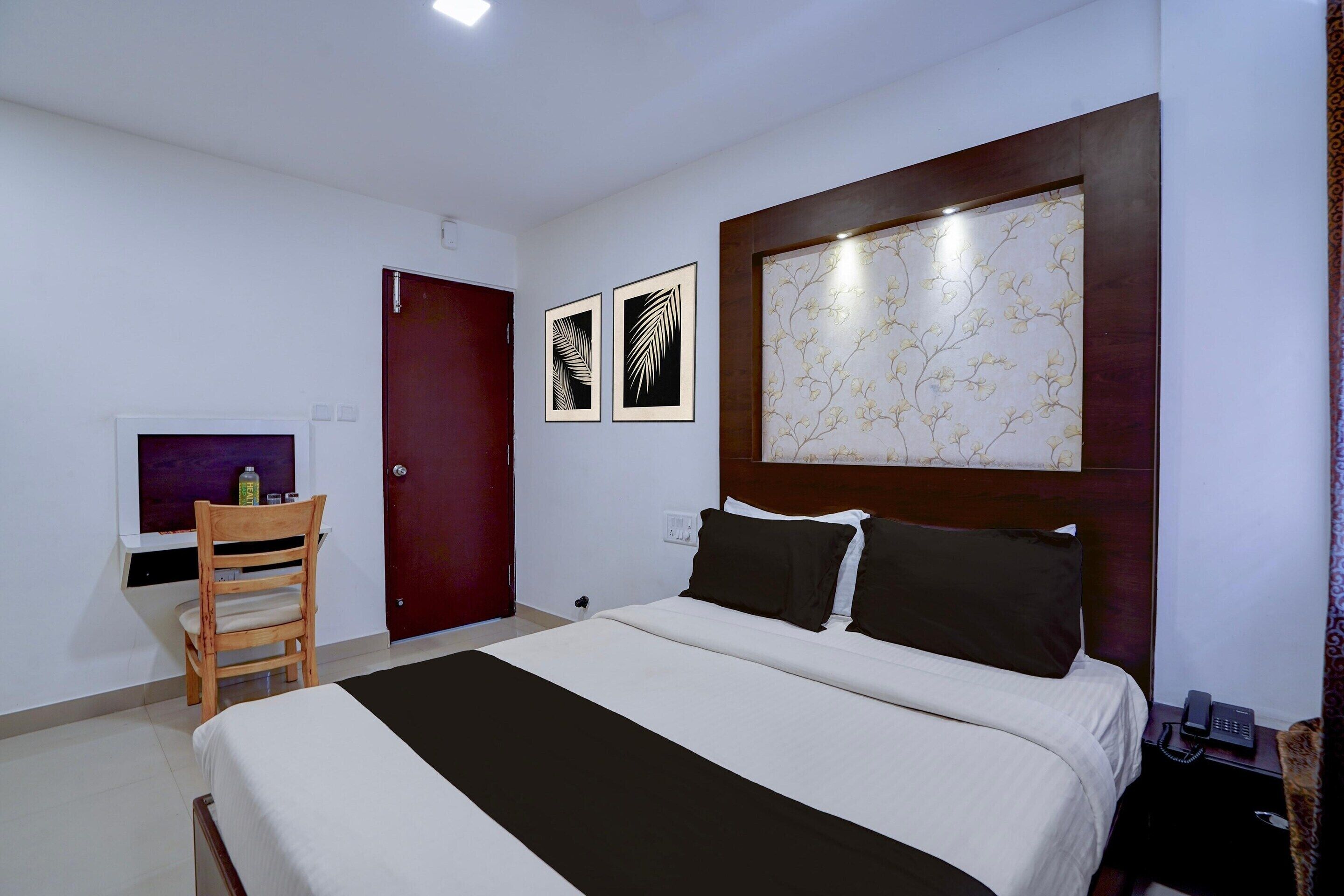Een hotelkamer met een bed, een houten stoel, een televisie en een deur.