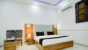 Un dormitorio moderno con estructura de cama de madera, una mesita de noche, una silla y una pequeña mesa con cafetera.