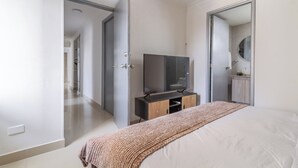 A bedroom with a bed, a TV on a stand, a wardrobe, and a mirror. - Altos del parque By Host Pro (Barranquilla)