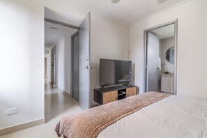 A bedroom with a bed, a TV on a stand, a wardrobe, and a mirror. - Altos del parque By Host Pro (Barranquilla)