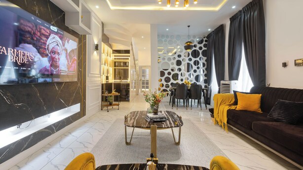 A modern living room with a flat-screen TV, a sofa, a coffee table, and a dining area.