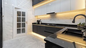 A modern kitchen with a black countertop, stainless steel appliances, and a white tiled backsplash.
