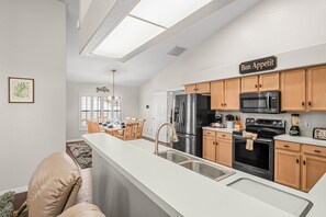 A modern kitchen with a central island, stainless steel appliances, and wooden cabinetry. - Loma Vista Escape - 4BR Pool Home Near Disney, Golf & Shopping (Davenport)