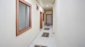 A hallway with large windows, doors, and a tiled floor. - Deluxebhagwati Palace (Mathura)
