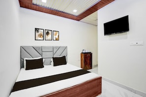 Ein modernes Hotelzimmer mit Bett, einem an der Wand befestigten Fernseher und Kunstwerken über dem Bett.
