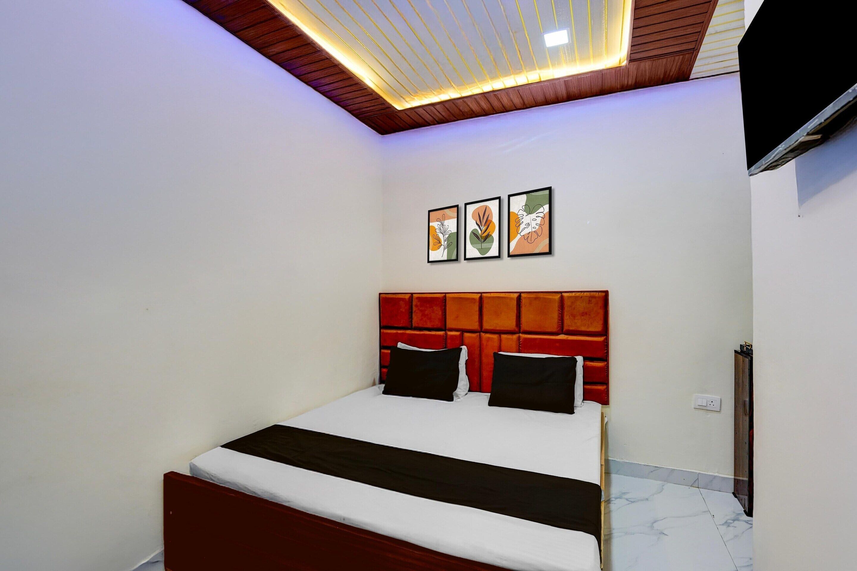Un dormitorio con una cama, techo de madera y tres cuadros en la pared.