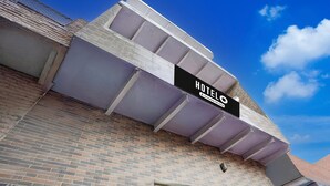 A hotel with a prominent sign, a brick facade, and a clear blue sky. - Deluxebhagwati Palace (Mathura)