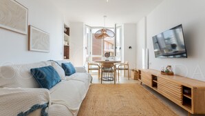 Ett modernt vardagsrum med en soffa, en tv, ett träskåp och en matplats med stolar och ett bord.