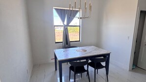 A dining area with a table, chairs, a chandelier, and a window with curtains. - Spacious 4-bedroom tranquil escape Lehigh Acres Near the Forum (Lehigh Acres)