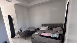 A modern bedroom with a large bed, a smaller sofa, and a tiled floor. - Spacious 4-bedroom tranquil escape Lehigh Acres Near the Forum (Lehigh Acres)