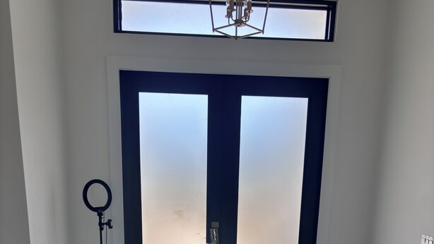 A room with a large door, a ring light, a trash bin, and a mat with a basketball court design. - Spacious 4-bedroom tranquil escape Lehigh Acres Near the Forum (Lehigh Acres)