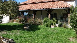 A house with a tiled roof, a covered porch, and a garden with various plants. - Cottage with private pool - 4 guests (Vanxains)