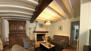 A living room with a fireplace, a sofa, a coffee table, and a television. - Cottage with private pool - 4 guests (Vanxains)