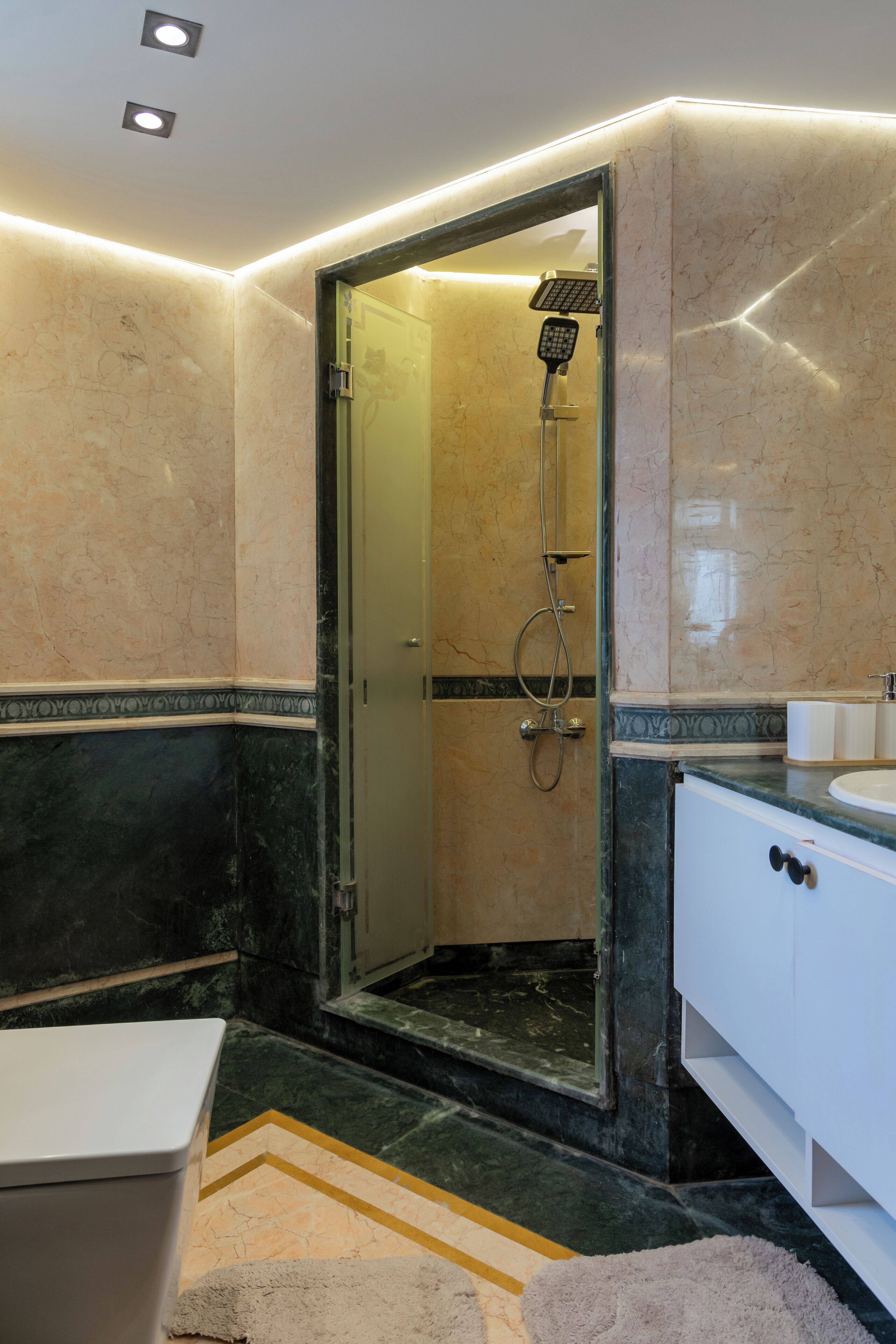 A modern bathroom with a glass-enclosed shower, a white sink, and a marble-tiled floor.