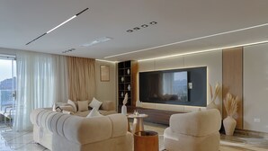 Un salon moderne avec un canapé, des fauteuils, une table basse et un téléviseur.