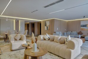 A modern living room with a sofa, chairs, a coffee table, and artwork on the walls. - ALSAWAH 4BR Luxury Nile Residence (Cairo)