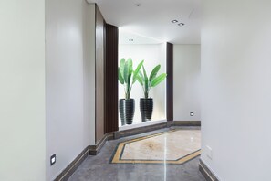 A hallway with a marble floor, a potted plant, and a window with blinds. - ALSAWAH 4BR Luxury Nile Residence (Cairo)