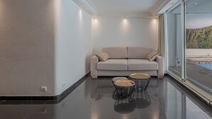 Een modern interieur met een bank, twee open tafels en een groot raam.