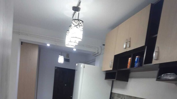 A compact kitchen with a refrigerator, microwave, and red coffee maker on the counter.