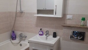 A bathroom with a bathtub, a sink with a mirror cabinet above, a toilet, and a shower.