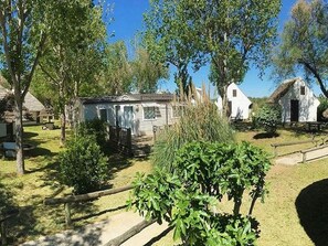 Un chalet rustique avec une clôture en bois, entouré d’arbres et sous un ciel dégagé.