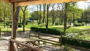 Un área de picnic techada con bancos y vistas a un parque con árboles y una masa de agua.