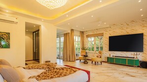 Un dormitorio espacioso con una cama grande, televisión, una consola verde y vistas al exterior.