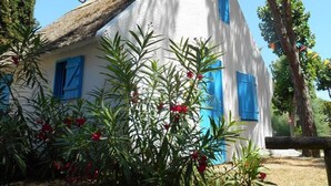 A white building with blue shutters, surrounded by greenery and trees. - Accessible mobile home, terrace - 6 guests (Lattes)