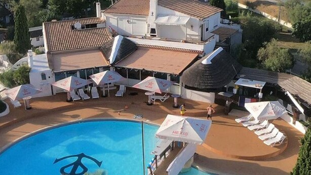 A swimming pool with a logo, sun loungers, umbrellas, and a building with a tiled roof. - Accessible mobile home, terrace - 6 guests (Lattes)
