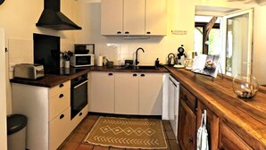 Una cocina compacta con armarios blancos, una campana extractora negra, un microondas, un tostador y una cafetera.