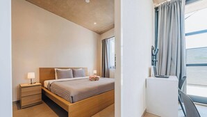 Ett modernt hotellrum med en säng i trä, sängbord, ett skrivbord och ett fönster med gardiner.