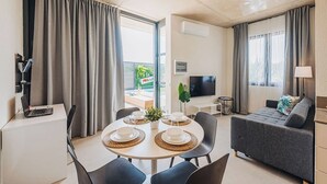 Ett modernt hotellrum med en matplats, en soffa, en TV och en balkong med utsikt.