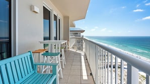 Un balcone con vista sull'oceano, un tavolo e una panca.