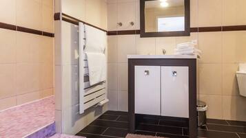 Une salle de bain avec un lavabo blanc, un miroir, un porte-serviettes et des toilettes.