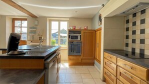 Een moderne keuken met houten kastjes, een inbouwoven, een magnetron en een koffieapparaat.