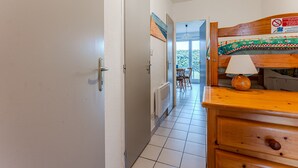 Een gang met een houten dressoir, een lamp en uitzicht op een balkon.