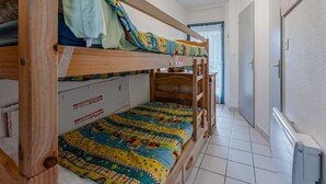 Een slaapkamer met een stapelbed, een kleurrijk quilt, een houten hoofdeinde en een plafondlamp.