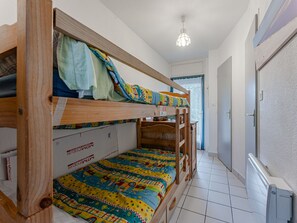 Ein Schlafraum mit Etagenbetten, einer farbenfrohen Stegdecke, einem Holz-Kopfteil und einer Deckenleuchte.