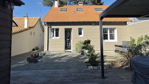 A residential building with a tiled roof, a front door, and a paved courtyard. - Renovated house with enclosed garden - 8 guests (Saint-Brevin-les-Pins)