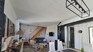 A modern living room with a staircase, a dining area, and a kitchen. - Renovated house with enclosed garden - 8 guests (Saint-Brevin-les-Pins)