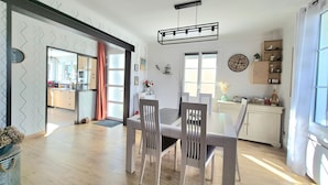 A modern kitchen with a dining area, wooden flooring, and a view into the adjacent living space. - Renovated house with enclosed garden - 8 guests (Saint-Brevin-les-Pins)