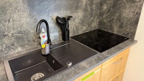 A kitchen with a black sink, a black stovetop, and wooden cabinets.