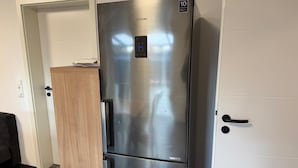 A stainless steel Samsung refrigerator with a digital control panel, a 10-year warranty, and a built-in ice maker.