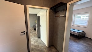 A hallway with a white door, a black refrigerator, and a window with blinds.