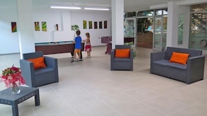 A lobby with grey sofas, a pool table, and a reception desk. - Apartamento en Calafell Cerca de la Playa (Calafell)