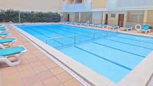 A swimming pool with lounge chairs and a building with balconies in the background. - Apartamento en Calafell Cerca de la Playa (Calafell)